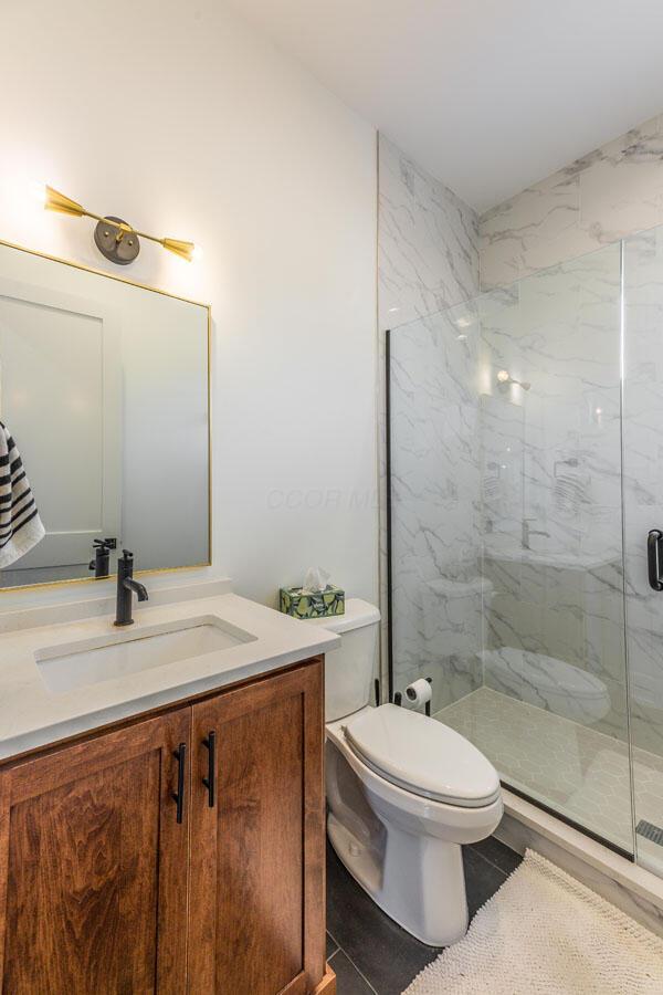 bathroom with vanity, tile patterned flooring, a shower with shower door, and toilet