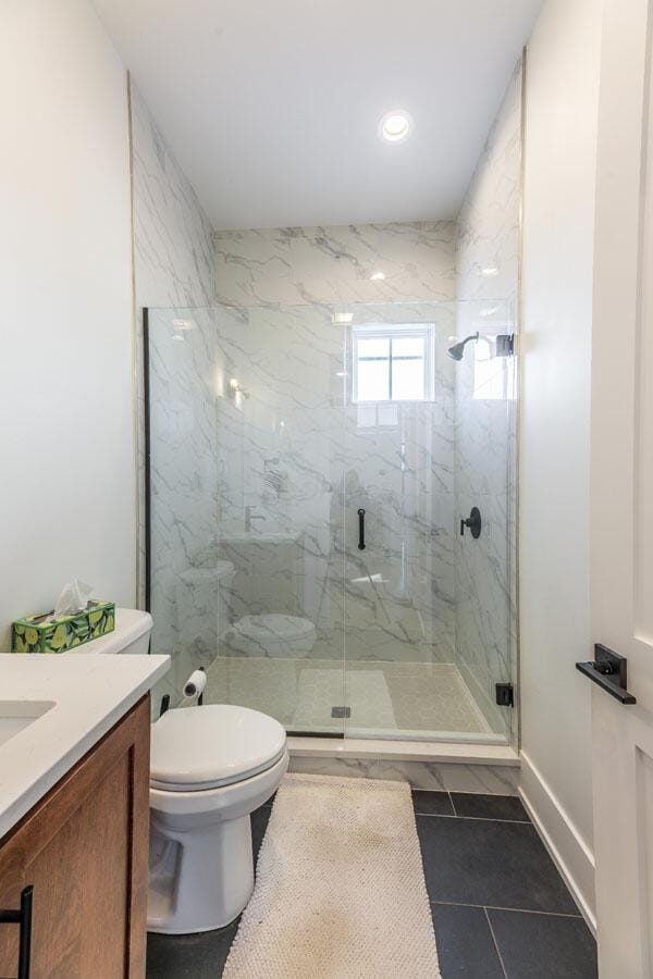 bathroom with vanity, tile patterned floors, toilet, and walk in shower