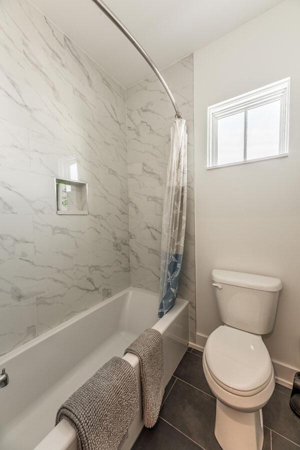 bathroom featuring shower / bathtub combination with curtain, tile patterned floors, and toilet