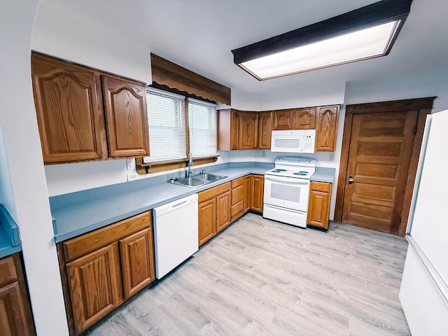 kitchen with white appliances, light hardwood / wood-style floors, and sink