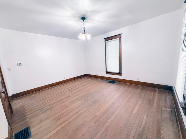 unfurnished room with hardwood / wood-style floors and a chandelier