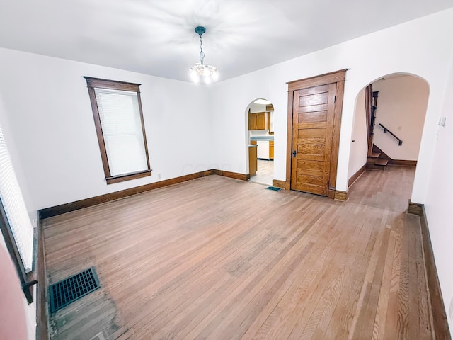 spare room with wood-type flooring and a chandelier