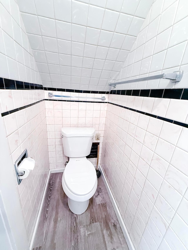 bathroom featuring lofted ceiling, toilet, tile walls, and hardwood / wood-style flooring