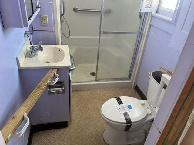 bathroom with toilet, a shower with door, and vanity