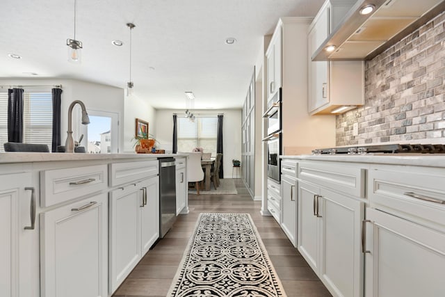 kitchen featuring white cabinetry, hanging light fixtures, a wealth of natural light, and wall chimney range hood