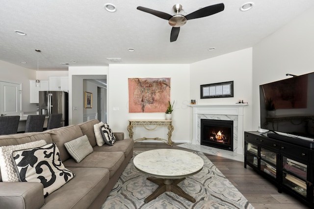 living room with ceiling fan, a high end fireplace, and hardwood / wood-style flooring