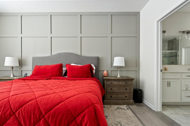 bedroom with light hardwood / wood-style flooring and ensuite bathroom