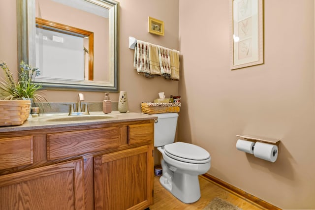 bathroom with toilet, wood-type flooring, and vanity