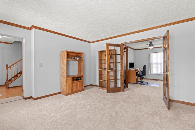 empty room with ceiling fan, carpet floors, ornamental molding, and a textured ceiling