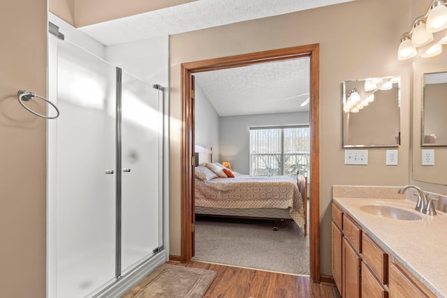 bathroom with wood-type flooring, vanity, a textured ceiling, and a shower with shower door