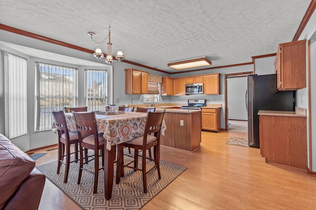 dining room featuring an inviting chandelier, ornamental molding, light hardwood / wood-style flooring, and sink