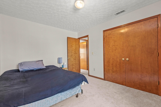 bedroom with a closet, light carpet, and a textured ceiling