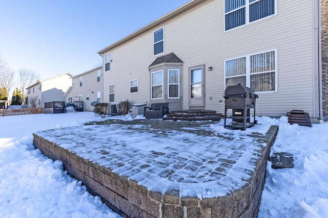 snow covered rear of property featuring central air condition unit