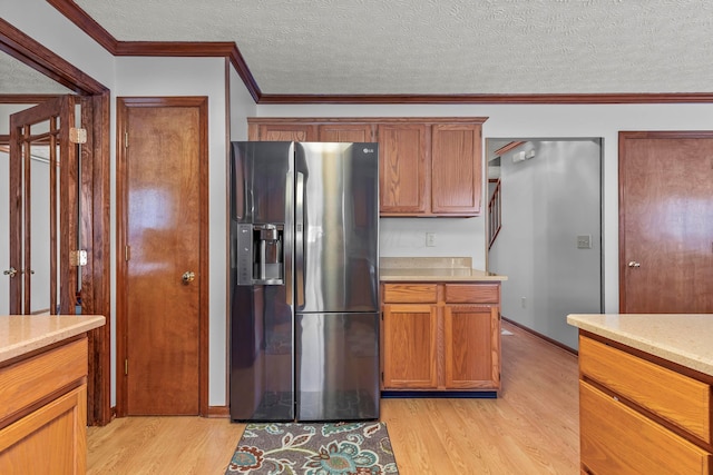 kitchen featuring a textured ceiling, ornamental molding, light hardwood / wood-style flooring, and stainless steel fridge