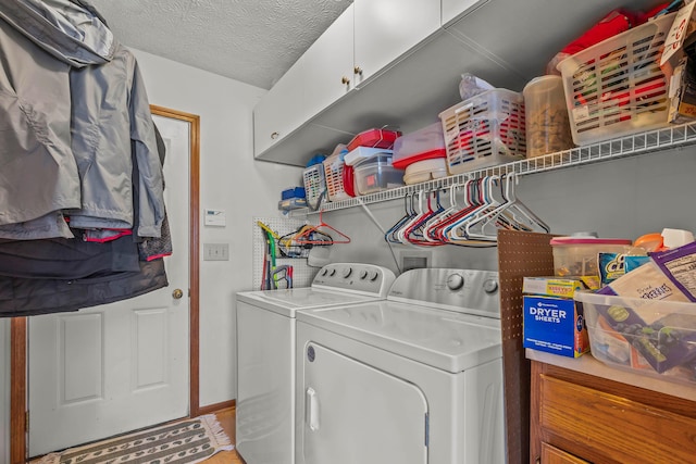 laundry area with a textured ceiling, cabinets, and independent washer and dryer