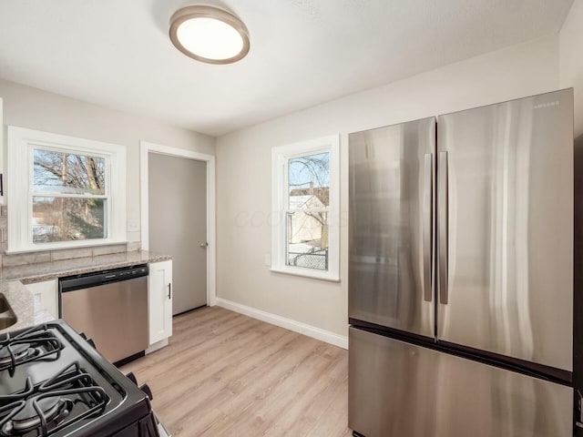 kitchen featuring white cabinets, a wealth of natural light, light hardwood / wood-style flooring, and appliances with stainless steel finishes