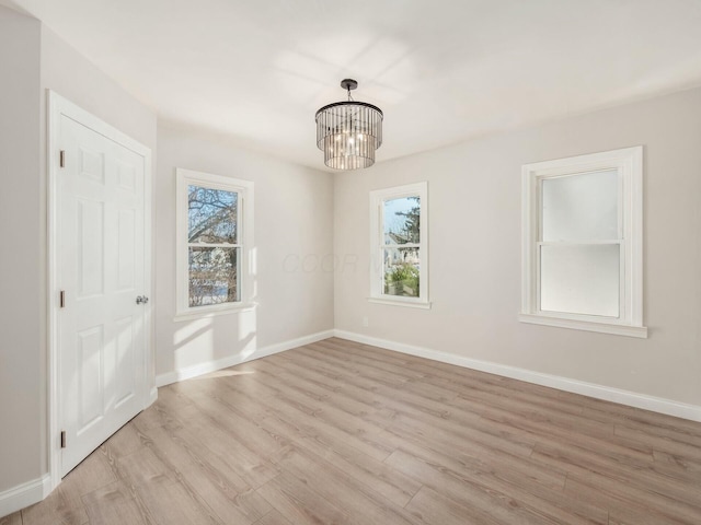 unfurnished room with an inviting chandelier and light hardwood / wood-style floors