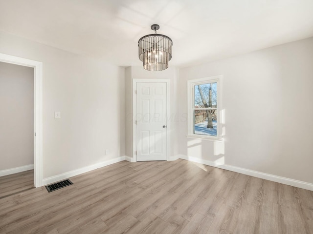 spare room with a chandelier and light hardwood / wood-style flooring