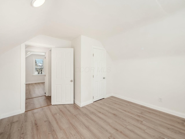 additional living space with light wood-type flooring and lofted ceiling