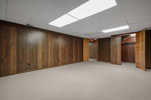 basement featuring a paneled ceiling and light colored carpet