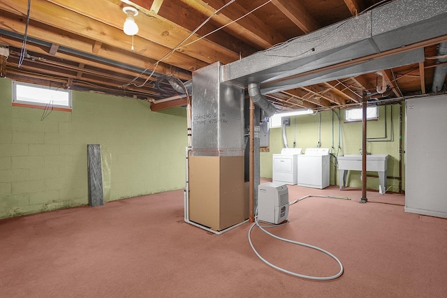 basement with light colored carpet, washing machine and dryer, a healthy amount of sunlight, and sink