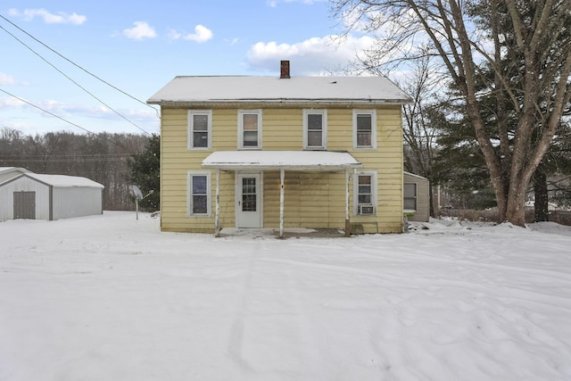 snow covered back of property with a storage unit and cooling unit