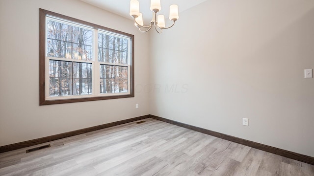 spare room featuring light hardwood / wood-style floors and an inviting chandelier
