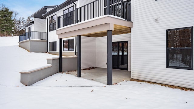 snow covered patio featuring a balcony