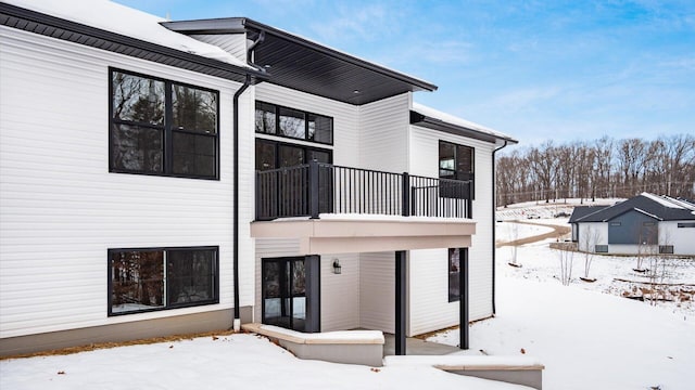 snow covered house featuring a balcony