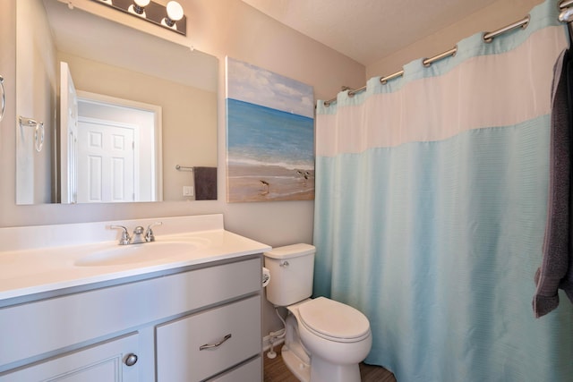 bathroom featuring toilet, vanity, and curtained shower