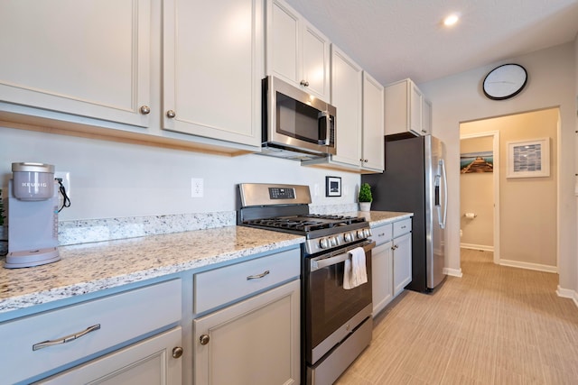 kitchen featuring light stone counters, white cabinetry, and stainless steel appliances