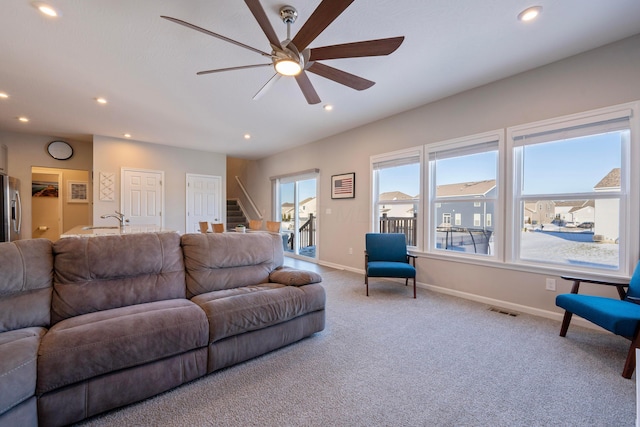 living room with ceiling fan, light colored carpet, and sink