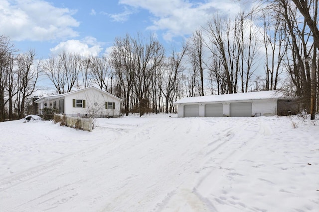 yard layered in snow featuring a garage and an outbuilding