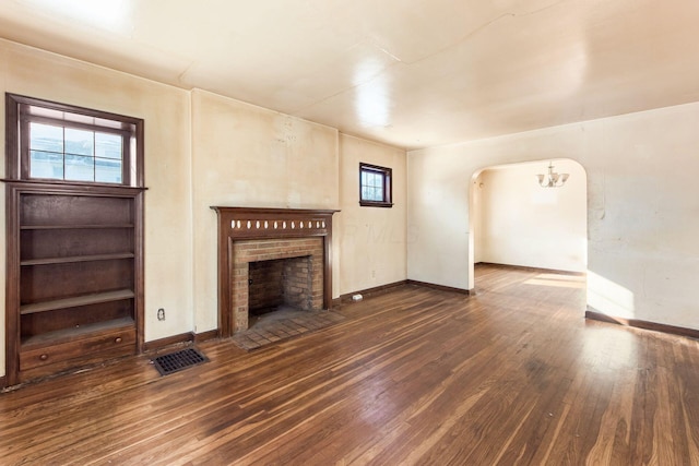 unfurnished living room with dark hardwood / wood-style flooring and a brick fireplace