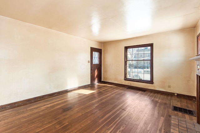 spare room featuring a brick fireplace and dark hardwood / wood-style floors