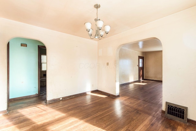 unfurnished room with hardwood / wood-style floors and an inviting chandelier