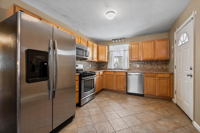 kitchen featuring sink, backsplash, appliances with stainless steel finishes, and light tile patterned flooring