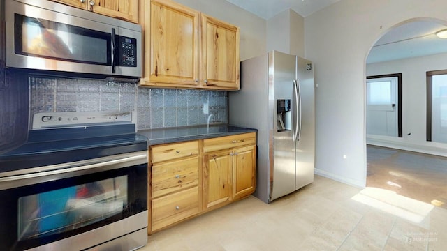 kitchen with stainless steel appliances, tasteful backsplash, and light brown cabinetry