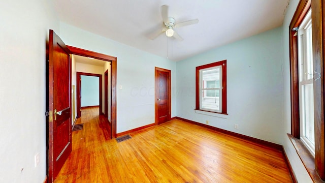 unfurnished bedroom featuring ceiling fan, light wood-type flooring, visible vents, and baseboards