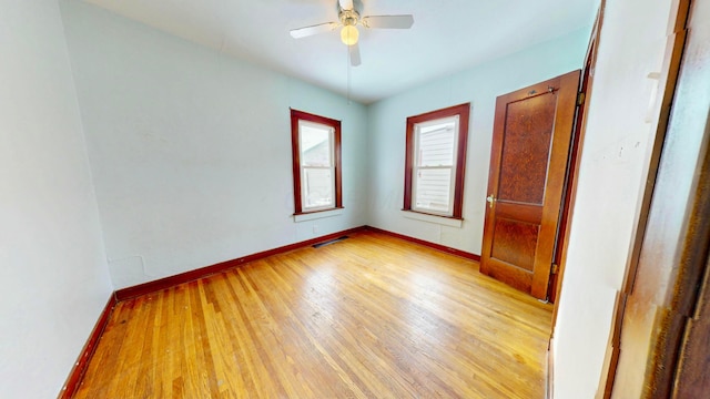 spare room featuring baseboards, ceiling fan, visible vents, and light wood-style floors