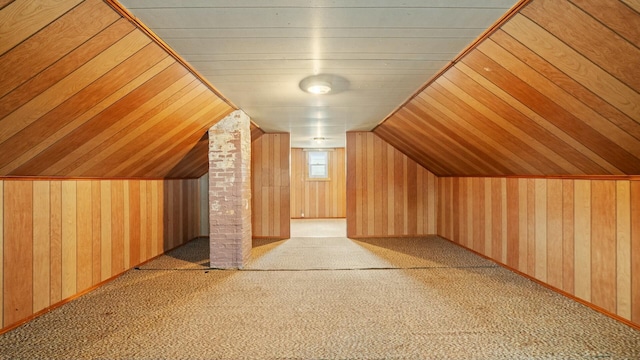 additional living space featuring lofted ceiling, wood walls, and carpet