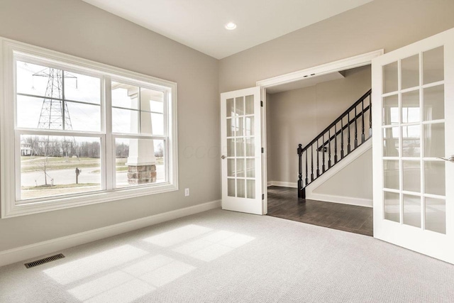 spare room featuring french doors and carpet