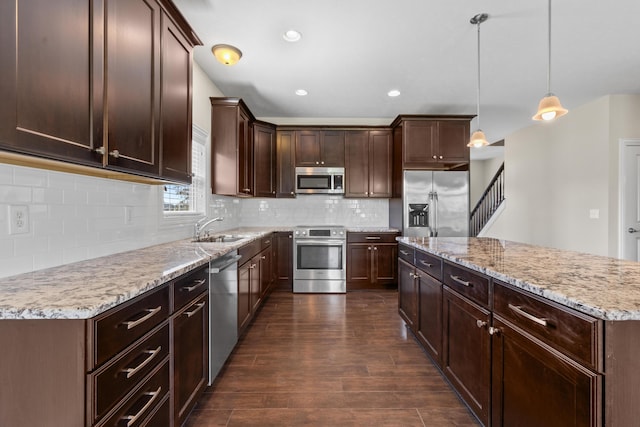 7136 Cabernet Ct, Dublin, OH 43016 - kitchen featuring appliances with stainless steel finishes, dark brown cabinetry, a kitchen island, dark wood-type flooring, and tasteful backsplash