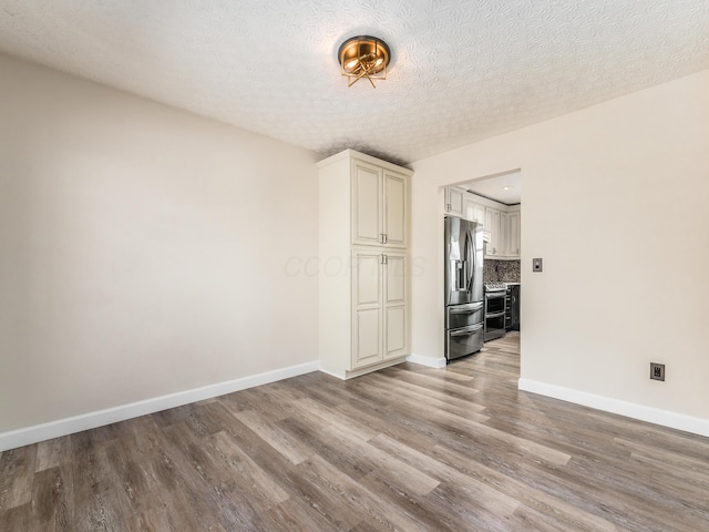 spare room with a textured ceiling and light hardwood / wood-style floors