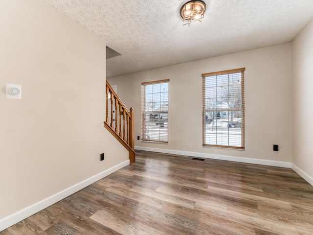 empty room with a textured ceiling and dark hardwood / wood-style flooring