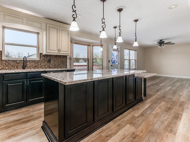 kitchen with ceiling fan, pendant lighting, sink, and a center island