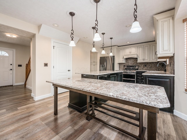 kitchen with pendant lighting, a center island, stainless steel appliances, premium range hood, and light stone counters