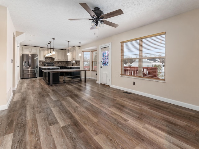 kitchen featuring a kitchen bar, stainless steel appliances, backsplash, a textured ceiling, and a kitchen island