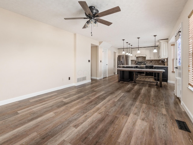 living room featuring ceiling fan, dark wood-type flooring, sink, and a textured ceiling