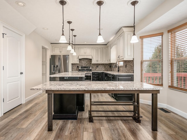 kitchen featuring custom exhaust hood, stainless steel appliances, backsplash, hanging light fixtures, and a center island